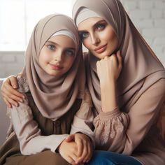 two women in hijabs are sitting on a couch and posing for the camera