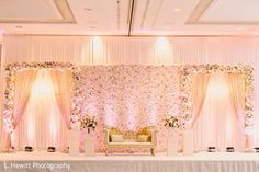 a wedding ceremony setup with flowers on the wall