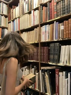 a woman standing in front of a book shelf filled with books