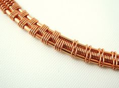 a close up of a bracelet on a white surface with gold colored metal wire and beads