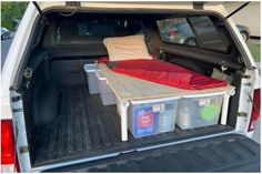 the back end of a white truck with its trunk open and luggage in the cargo area