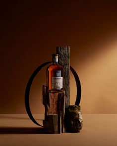 a bottle of whiskey sitting on top of a wooden stand next to a rock and barrel