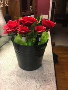 a black bucket filled with red flowers on top of a counter