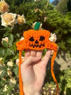 a hand holding an orange crocheted pumpkin hat