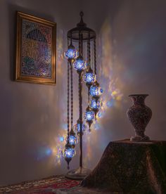 a decorative light fixture in the corner of a room next to a painting and vase