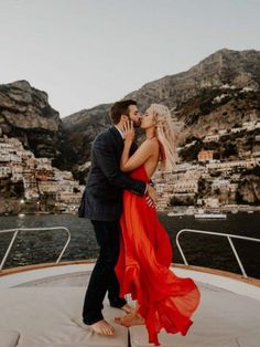 a man and woman kissing on the back of a boat