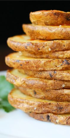 a stack of baked potatoes sitting on top of a white plate next to a green leafy plant