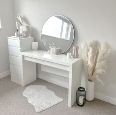 a white desk with a mirror, vase and other items on it in a room