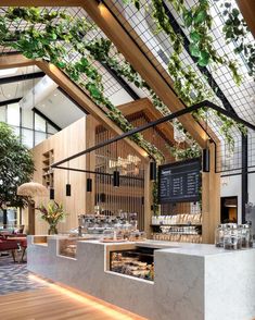 the inside of a restaurant with plants growing on the wall and wooden flooring, along with glass walls