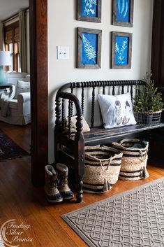 a black bench with baskets on it in front of three pictures and a rug underneath