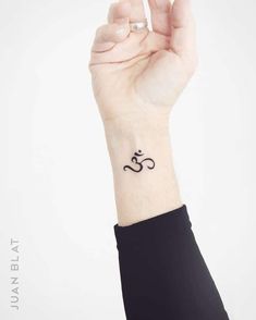 a woman's wrist tattoo with an om symbol on the left side of her arm