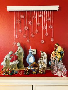 a red wall with snowflakes hanging from it's side and figurines on top