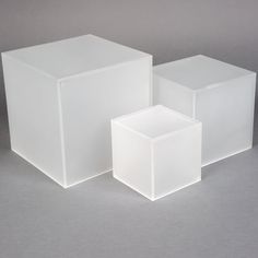 three white cubes sitting next to each other on a gray surface with no one in the photo