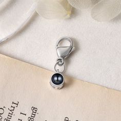 a key chain with a black pearl hanging from it's end on top of a piece of paper