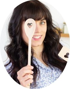 a woman holding a wooden spoon with a heart on it