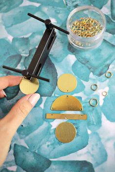 a person is making gold earrings with scissors and other accessories on a table next to them