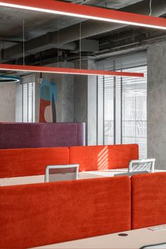 an office cubicle with orange and pink couches in front of a large mirror