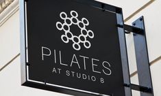 the sign for pilates at studio 8 is hanging from the side of a building