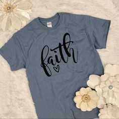 This Listing Is For A Golly Wally Designs Original! The Word “Faith” Is Screen Printed Onto A Stone Blue Gildan Brand Ultra Cotton Tee. With A Comfy Standard Tee Fit, This Design Sends A Powerful Message In A Simple Way! Garment Details: 100% Cotton Mashing Wash/Tumble Dry Note: Listing Is For T-Shirty Only; Flower Props Not Included. Flower Props, Faith Tshirts, Faith Tees, Print Fonts, A Script, Apparel Brand, Next Level, Womens Clothing Tops, Design Details