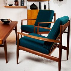 a teal chair sitting in front of a wooden table with a bowl on it