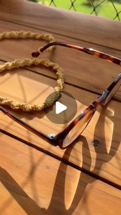 a pair of glasses sitting on top of a wooden table next to a roped eyeglass holder