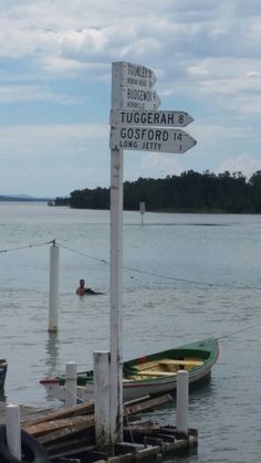 there are many signs on the dock pointing to different places in the water and people swimming