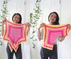 a woman holding up a pink and yellow crochet square shawl in front of her face