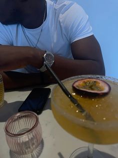 a man sitting at a table in front of a plate with food and drinks on it