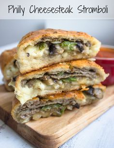 two sandwiches stacked on top of each other with cheesesteak in the middle and broccoli inside