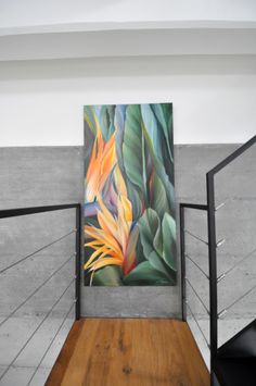 an abstract painting hangs on the wall next to a wooden floor and metal railings