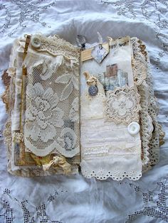 an open book with lace and buttons on it sitting on top of a white sheet