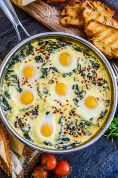 an egg and spinach casserole in a pan with bread on the side