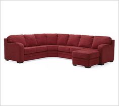 a large red sectional couch sitting on top of a white floor next to a chair