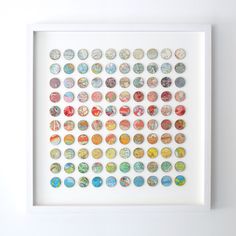 a white framed artwork with many different colored buttons on the front and back of it