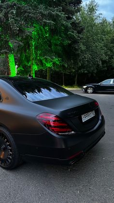 a black car parked in front of some trees