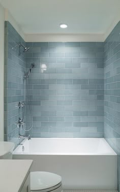 a white toilet sitting next to a bath tub in a bathroom under a light fixture