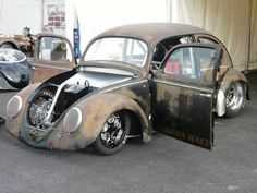 an old, rusty car is parked in a lot next to other antique cars and motorcycles