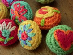 several crocheted balls with flowers and hearts on them