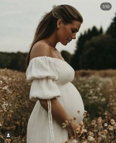 a pregnant woman is standing in a field