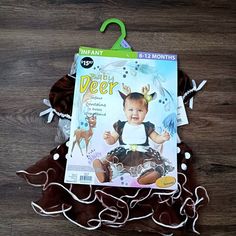 an infant's deer costume is displayed on a wooden floor with string and tags