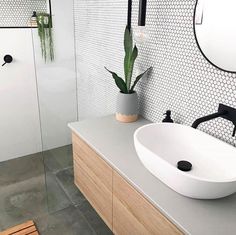 a white sink sitting next to a wooden counter top under a mirror in a bathroom