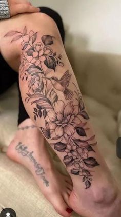 a woman's leg with flowers and birds on it, in black and white