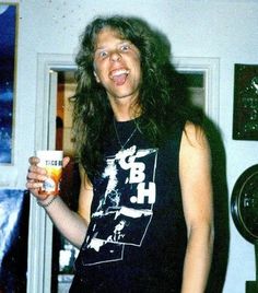 a man with long hair is holding a drink