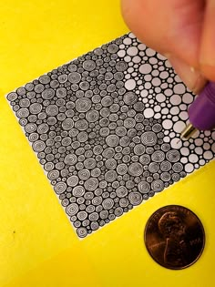 a coin is next to a piece of black and white paper with circles on it