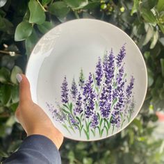 a person holding a plate with purple flowers painted on it