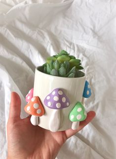 a hand holding a potted plant with small mushrooms on the outside and dots on the inside