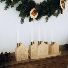 some candles are sitting on a mantle with christmas decorations