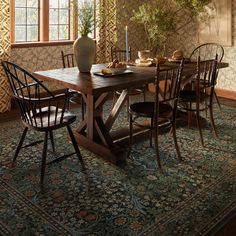 a dining room table with chairs and a vase filled with flowers on top of it