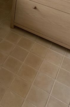 a wooden dresser sitting on top of a tiled floor