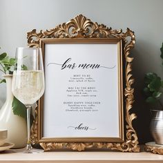 there is a framed menu next to a glass of wine on the table with other items